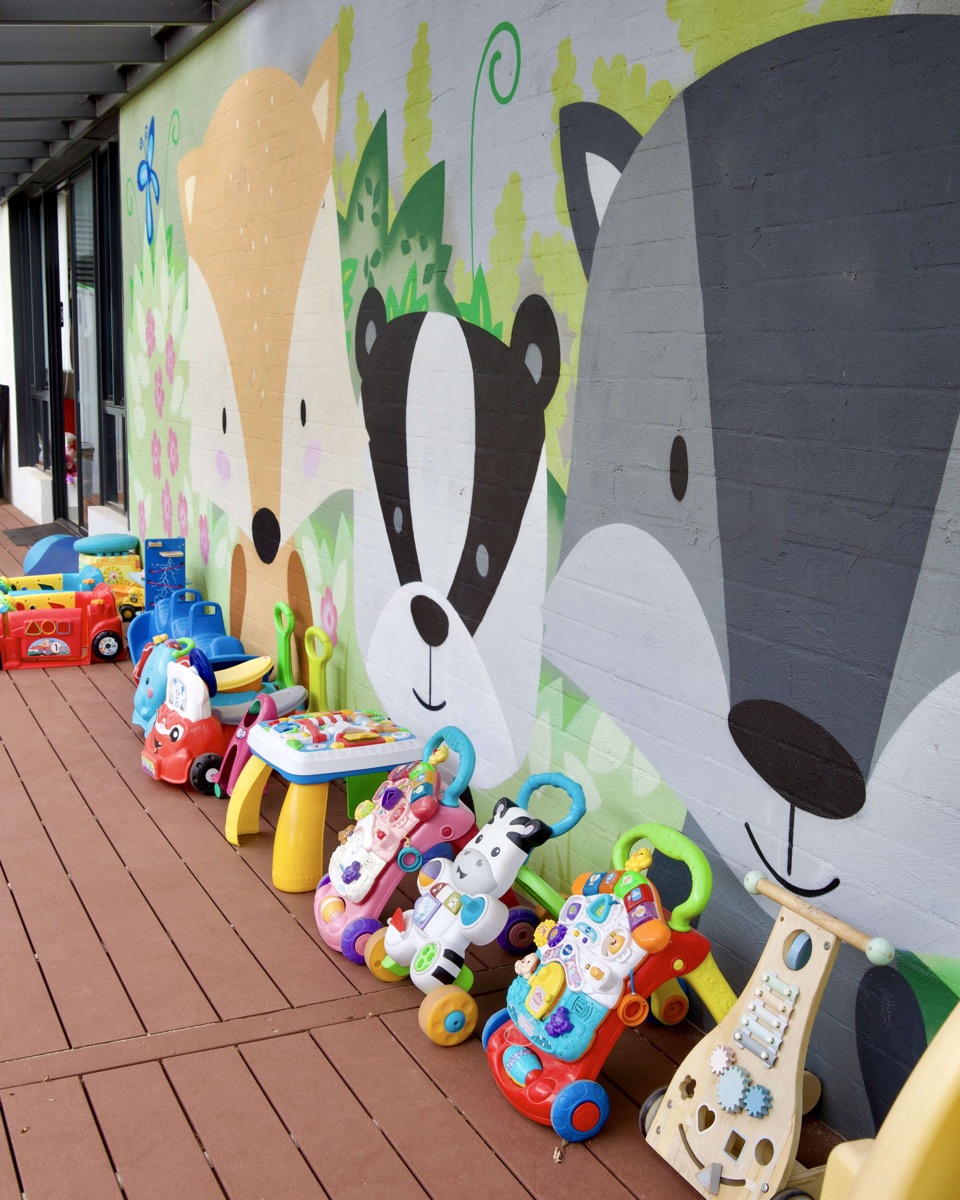 The covered deck at Cubs Corner, with an animal mural and ride-on toys