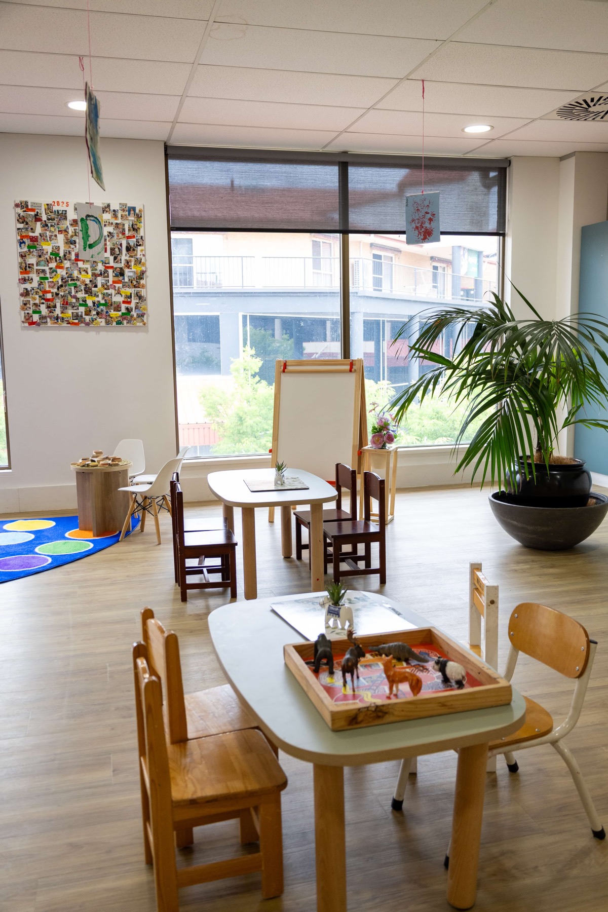 A bright room for older children at Cubs Corner with a lion savanna mural, tables and an easel