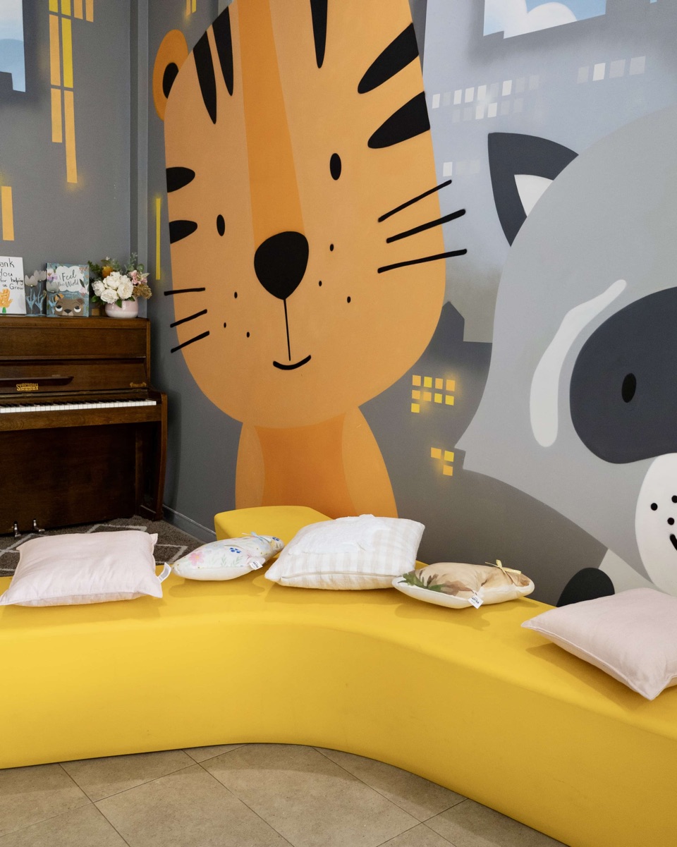 The foyer reading nook at Cubs Corner, with a yellow bench, cushions and a tiger mural